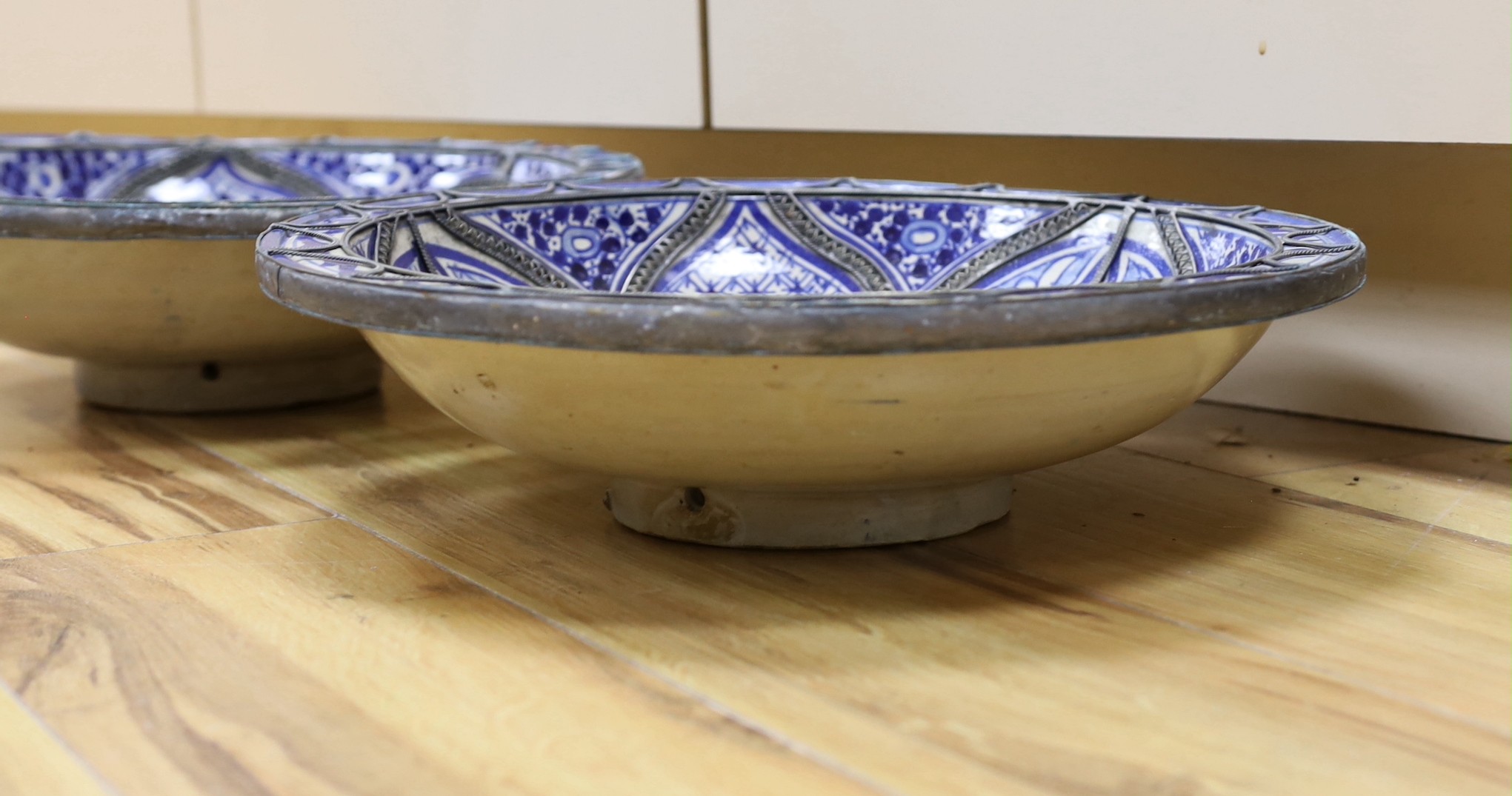 A pair of Moroccan metal bound pottery dishes, 39cm diameter